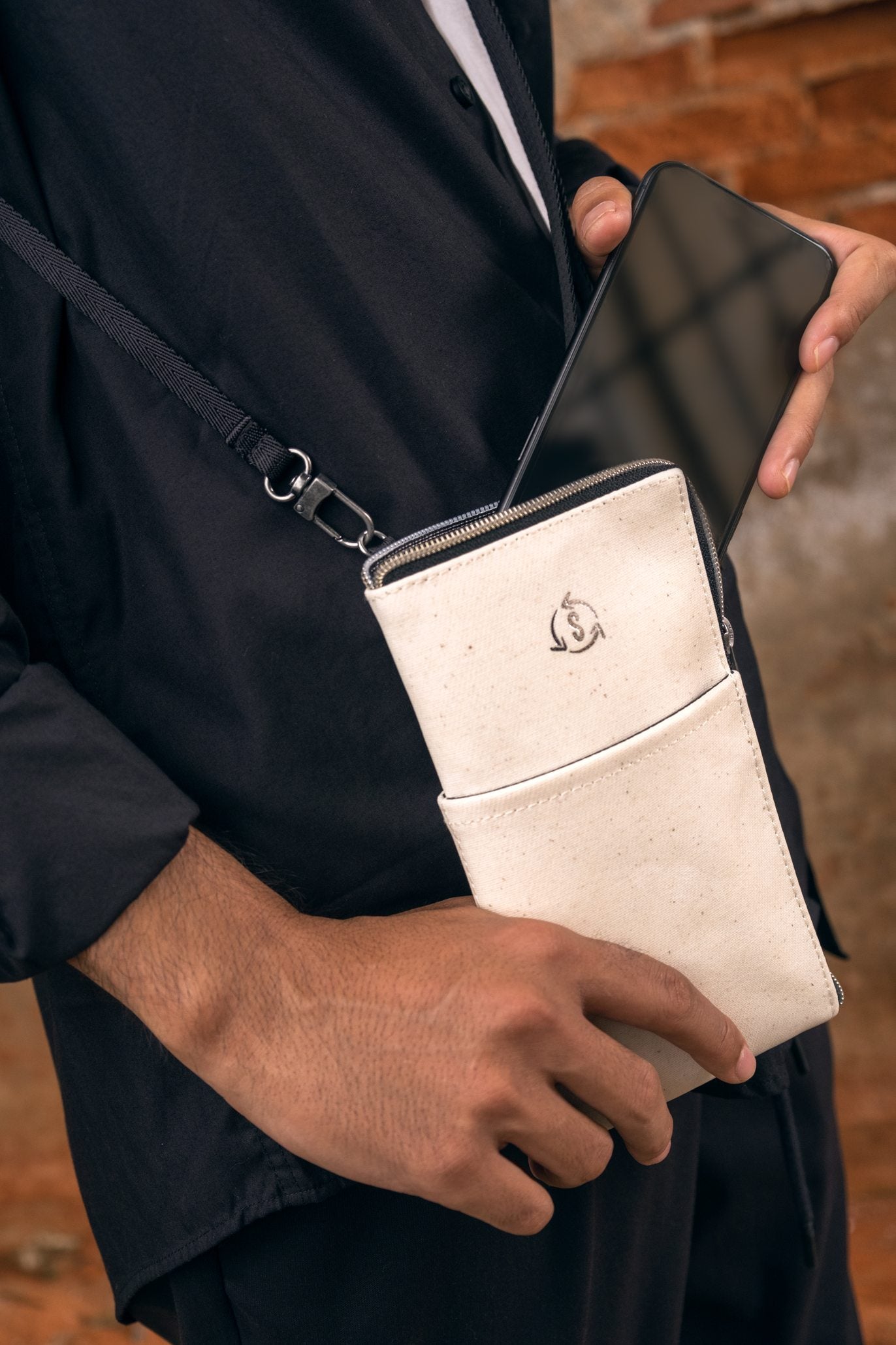 A person holding a Mate phone bag in Natural White IKI material