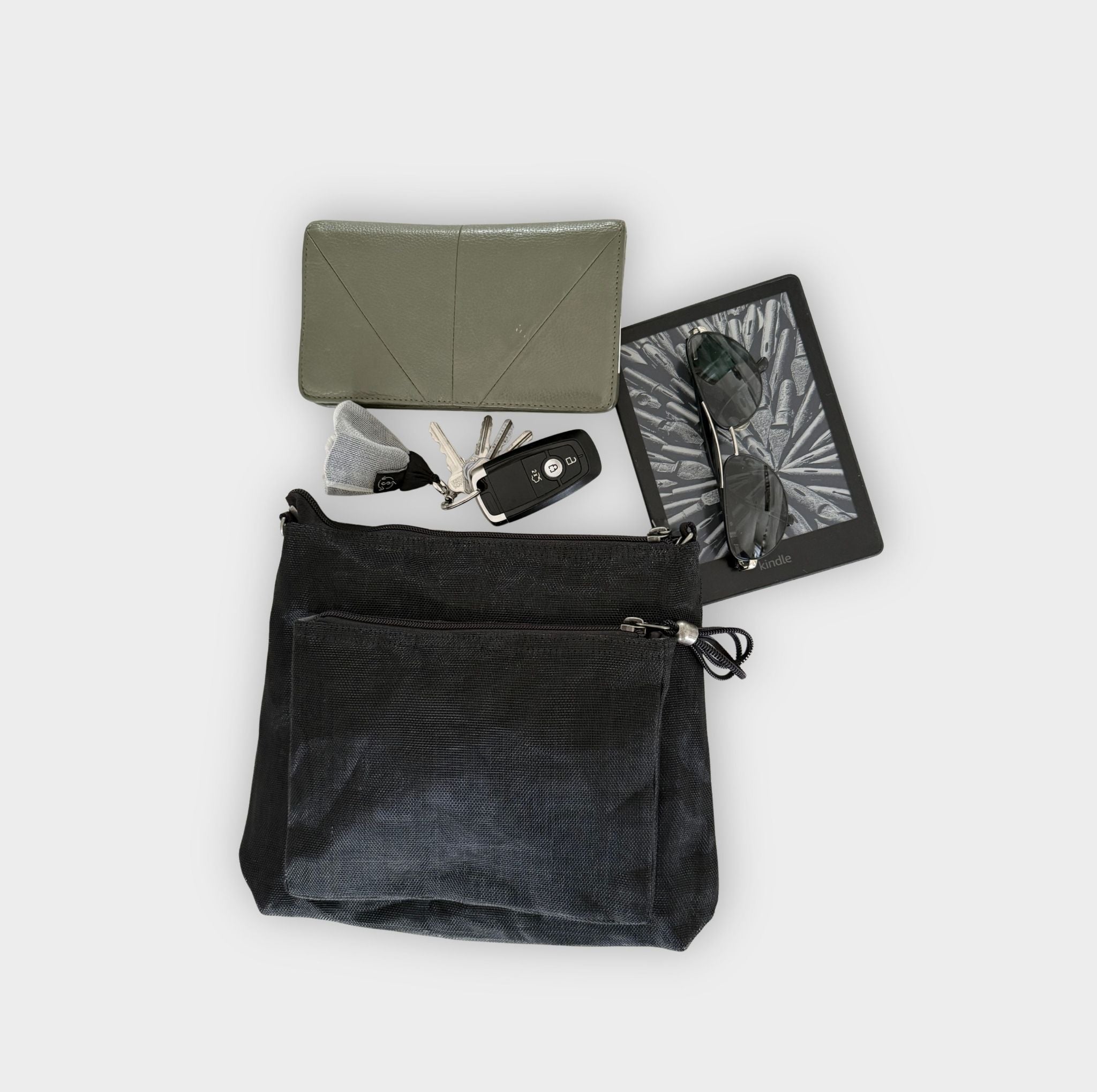 Black Smateria bustle crossbody bag with a grey purse and items on a light grey background