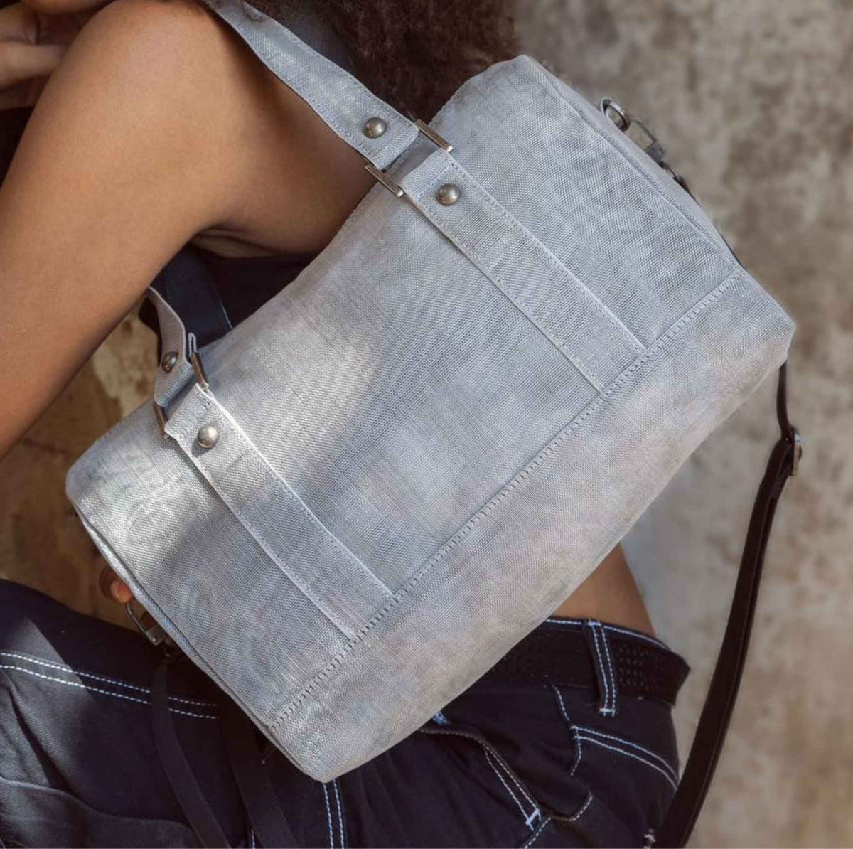 A woman holding a Smateria Carry-On duffle bag in Silver net