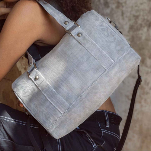 A woman holding a Smateria Carry-On duffle bag in Silver net