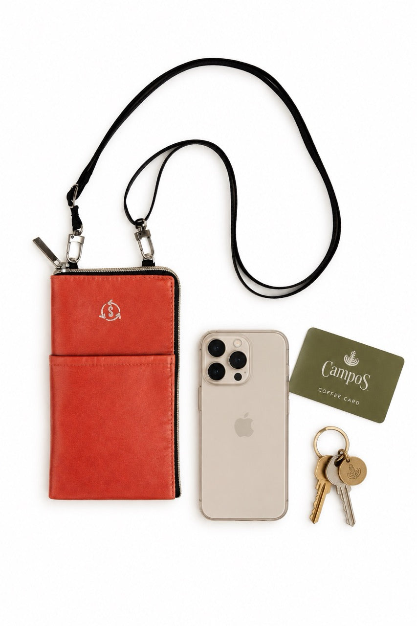 A Smateria Mate phone bag in Terracotta photographed alongside a white phone, campos coffee card and some keys