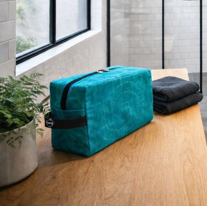 A Smateria RAM Vanity bag on a wooden bench with black towels and a plant in the background.