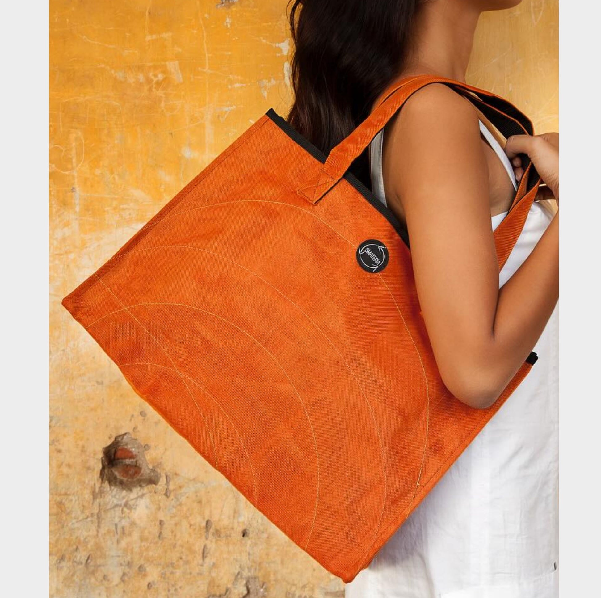 Smateria shopper tote bag held by a person against a textured yellow background